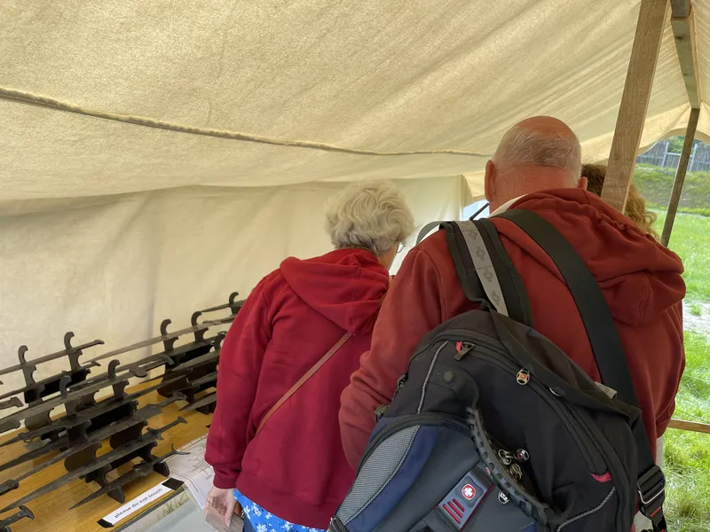 Visitors leaning over the table to look closely at the reconstructed blades