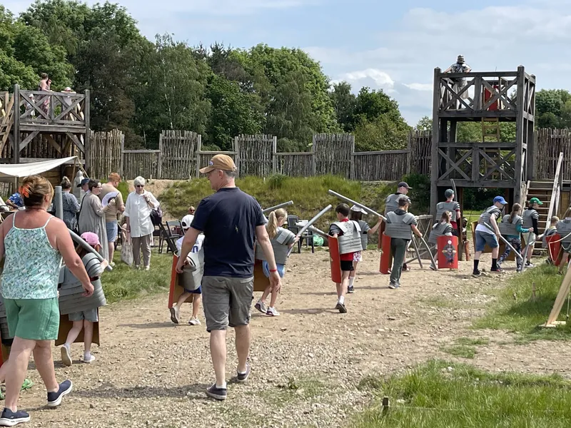 Visitors walking the gravel path towards the fort's timber towers