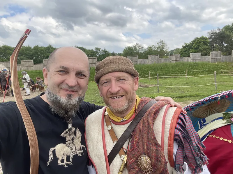 Two men photographed together, one in steppe dress carrying a bow