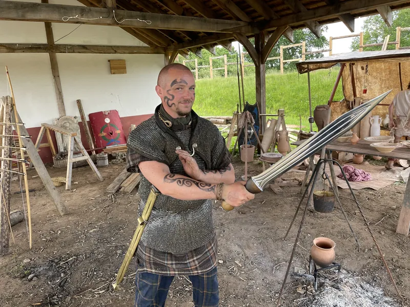 A smith at the forge holding a newly worked blade