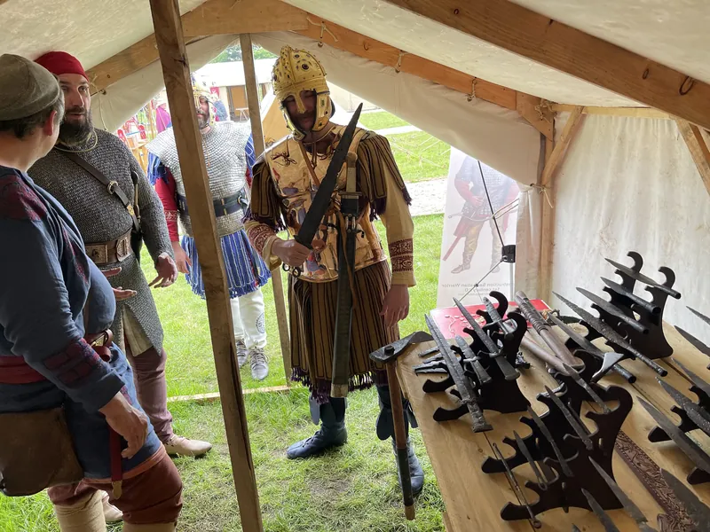 Reconstructed blades laid out on the table, a re-enactor in scale armour standing behind