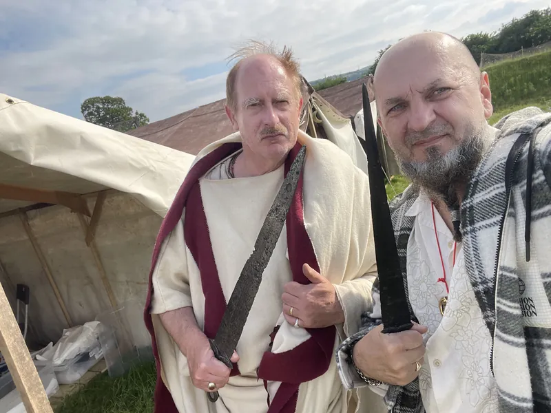 Two Society members in Roman tunics, each holding a sword