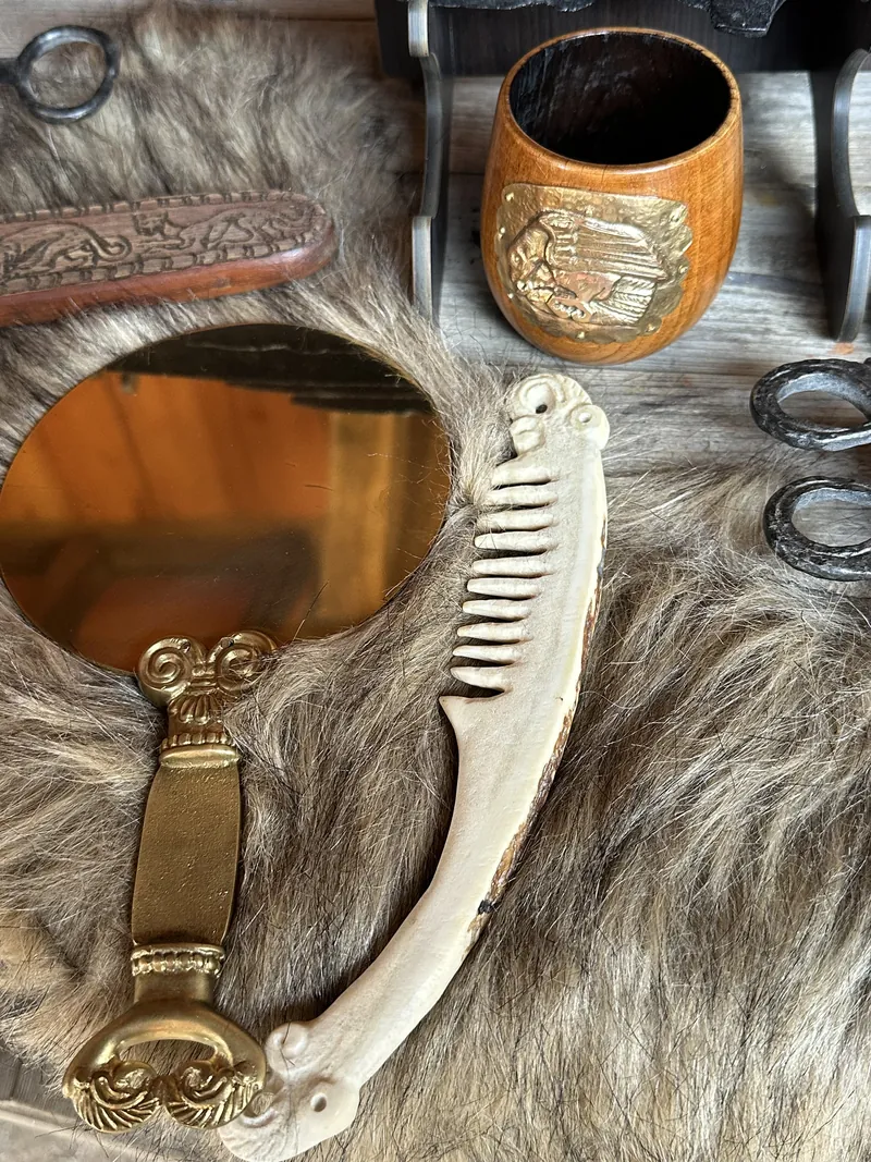 A gilded mirror and a comb of bone and gilt bronze laid on fur among smaller finds