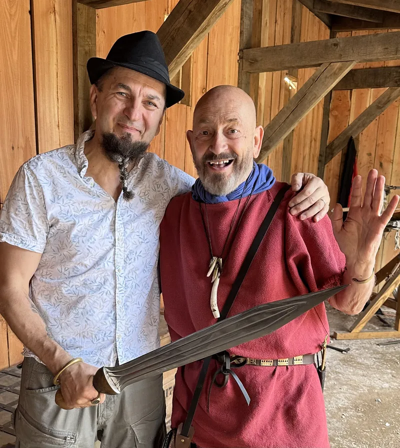 Two men holding a long blade between them