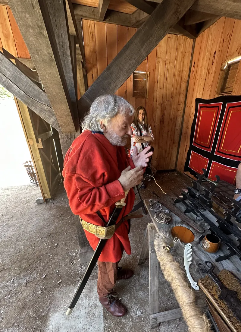 A Society member in a red tunic working at the table of blades
