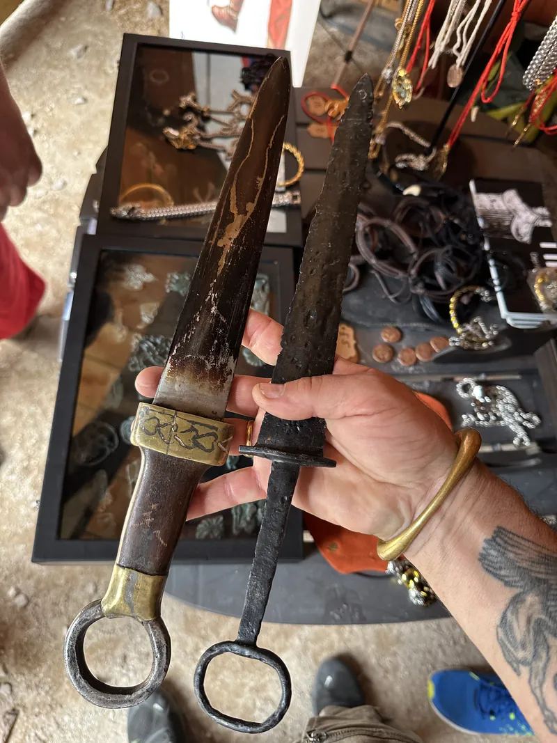 Hands holding a ring-pommel dagger with a decorated grip