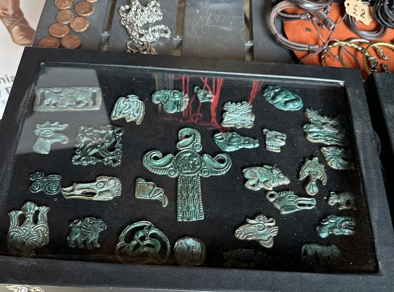 A tray of bronze harness fittings and openwork plaques, green with age