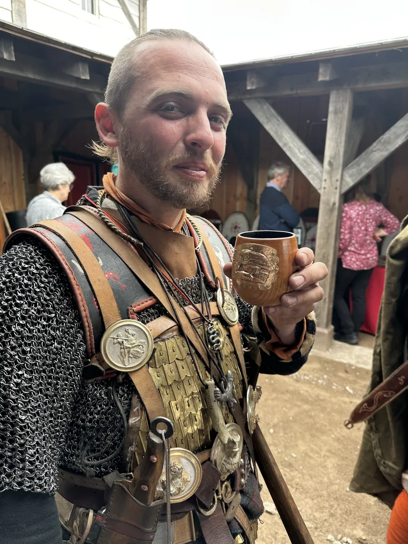 A re-enactor in mail and scale armour holding a drinking cup