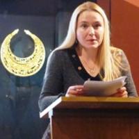 Dr Hanna Vertiienko speaking beside a display of Scythian gold