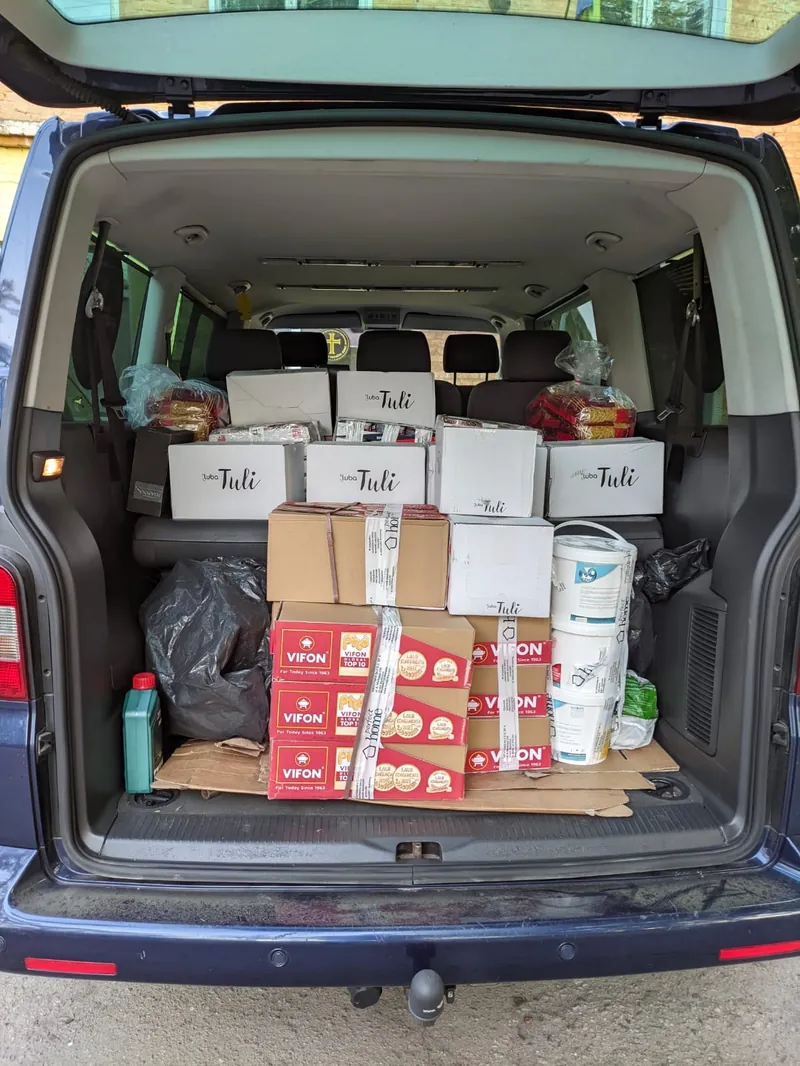 The rear of a van filled with boxes of tinned food, bottled water and household supplies