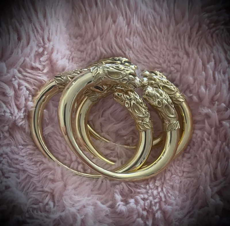 A pair of gilded bracelets finished with confronted animal-head terminals