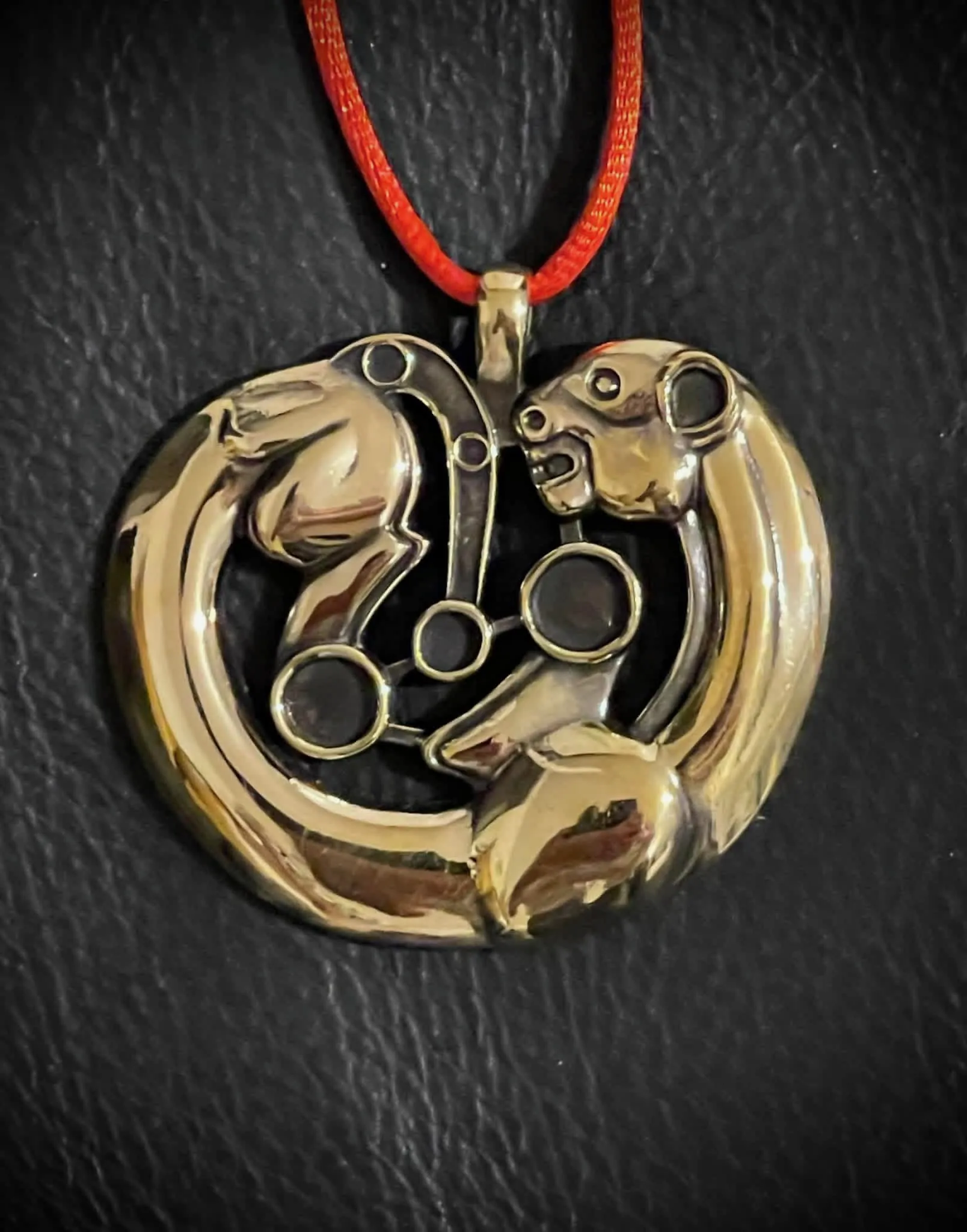 An openwork pendant of two confronted beasts, hung on a red cord