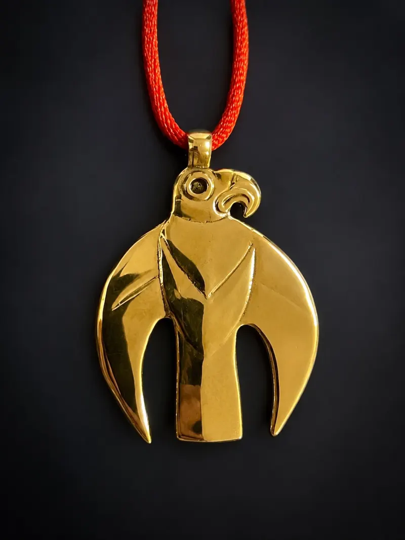 Modern gold replica of a steppe pendant in the animal style, on a red cord